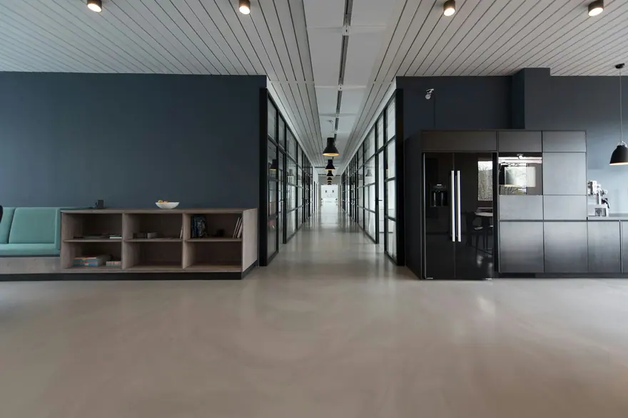 Open office with glass-walled rooms, a kitchenette and teal bench seating