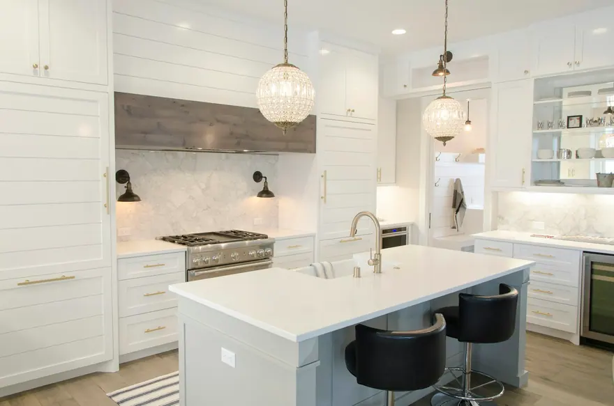White kitchen with an island, bar stools and pendant lights